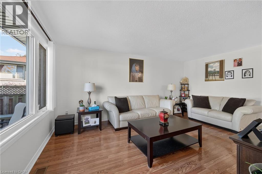 Living space featuring wood-finish flooring, neutral walls, and a large multi-pane window - 411 Queen Victoria Drive, Hamilton, ON