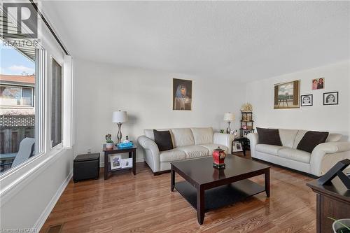 Living space featuring wood-finish flooring, neutral walls, and a large multi-pane window - 411 Queen Victoria Drive, Hamilton, ON 