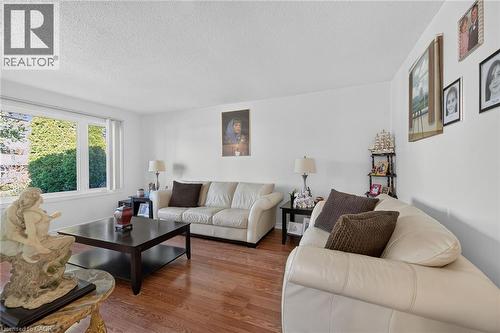 Living area featuring wood-finish flooring and a multi-pane window with vertical blinds - 411 Queen Victoria Drive, Hamilton, ON 