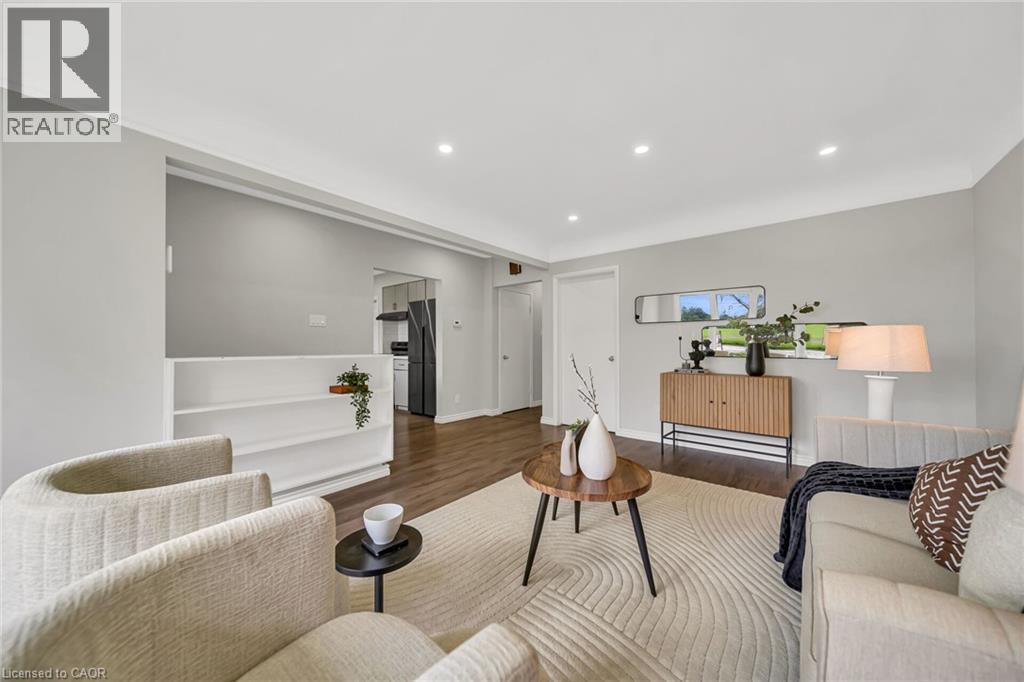 Recessed lighting, wood-finish flooring, half wall with shelving, gray wall tones, and white trim throughout - 284 Cedar Crescent, Cambridge, ON - Indoor Photo Showing Living Room