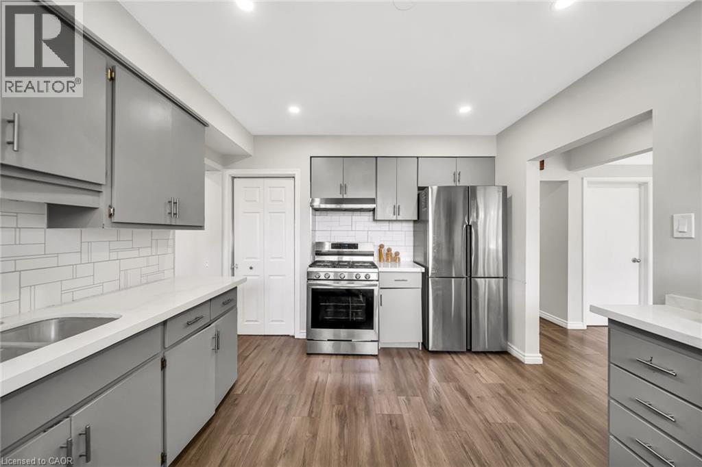 Kitchen featuring wood-finish flooring, recessed lighting, stainless steel appliances, grey cabinetry, and a white tile backsplash - 284 Cedar Crescent, Cambridge, ON - Indoor Photo Showing Kitchen With Upgraded Kitchen