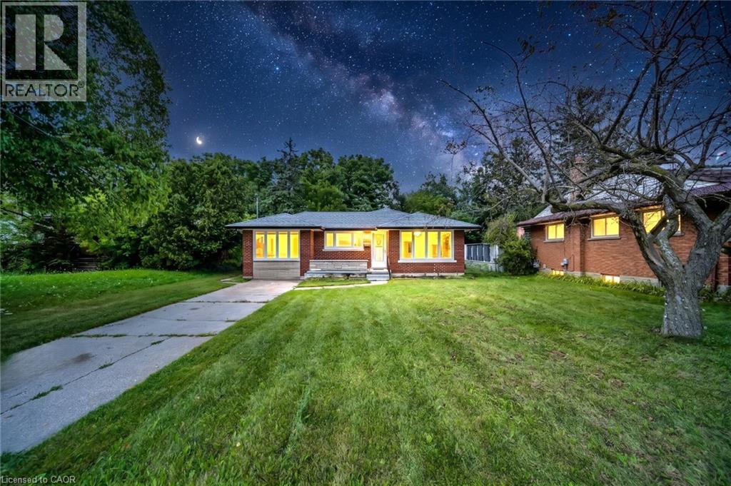 Brick exterior with a gabled roofline, expansive front lawn, mature trees, and a concrete driveway - 284 Cedar Crescent, Cambridge, ON - Outdoor
