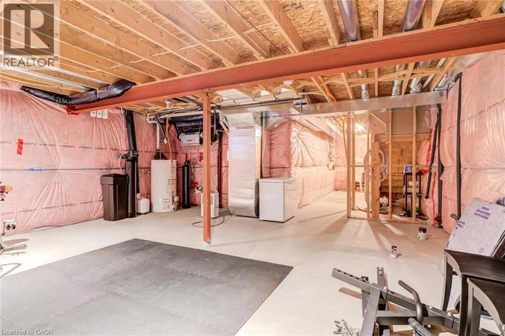 Unfinished basement featuring white refrigerator, gas water heater, and a water softener system - 239 Cranbrook Street, Kitchener, ON - Indoor Photo Showing Basement