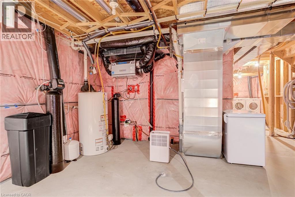 Unfinished basement featuring water heater, a water softener system, and washer / dryer - 239 Cranbrook Street, Kitchener, ON - Indoor Photo Showing Laundry Room
