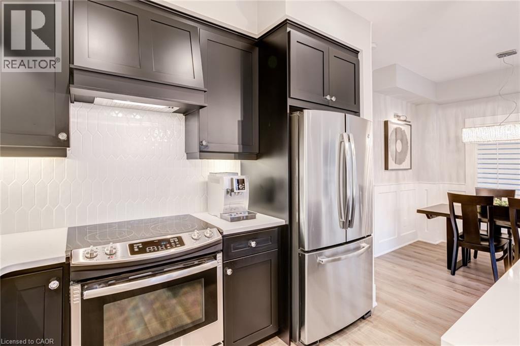 Kitchen featuring stainless steel appliances, light wood-style flooring, a wainscoted wall, a decorative wall, and light stone countertops - 239 Cranbrook Street, Kitchener, ON - Indoor Photo Showing Kitchen