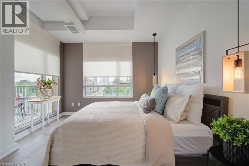 Bedroom featuring wood-finish flooring, exposed ductwork, and a built-in wall-mounted light fixture - 191 King Street S Unit# 607, Waterloo, ON - Indoor Photo Showing Bedroom