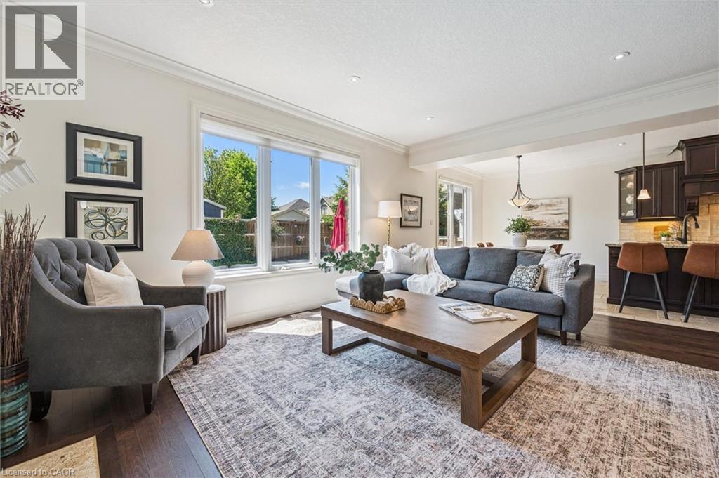 Spacious living area featuring large windows, dark wood-finish flooring, recessed lighting, and crown molding. - 828 Copper Ridge Drive, Waterloo, ON - Indoor Photo Showing Living Room