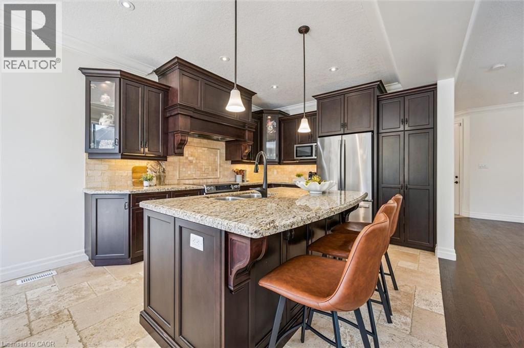 Kitchen featuring dark wood cabinetry, a granite countertop island, stainless steel appliances, recessed lighting, and tile flooring. - 828 Copper Ridge Drive, Waterloo, ON - Indoor Photo Showing Kitchen With Double Sink With Upgraded Kitchen