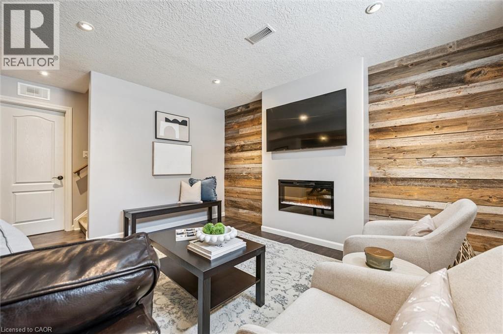 Living area featuring a modern fireplace insert, recessed lighting, and a prominent wood-panel accent wall. - 828 Copper Ridge Drive, Waterloo, ON - Indoor Photo Showing Living Room With Fireplace
