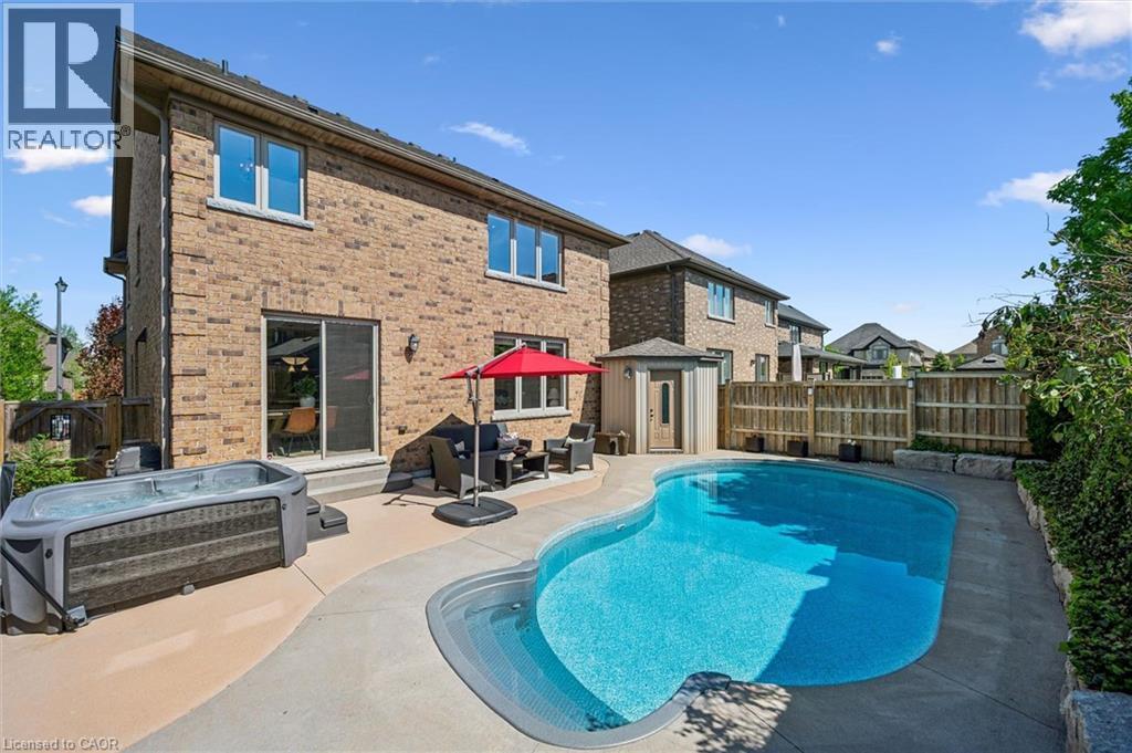 Brick exterior with a large curved swimming pool and integrated steps. - 828 Copper Ridge Drive, Waterloo, ON - Outdoor With In Ground Pool With Exterior