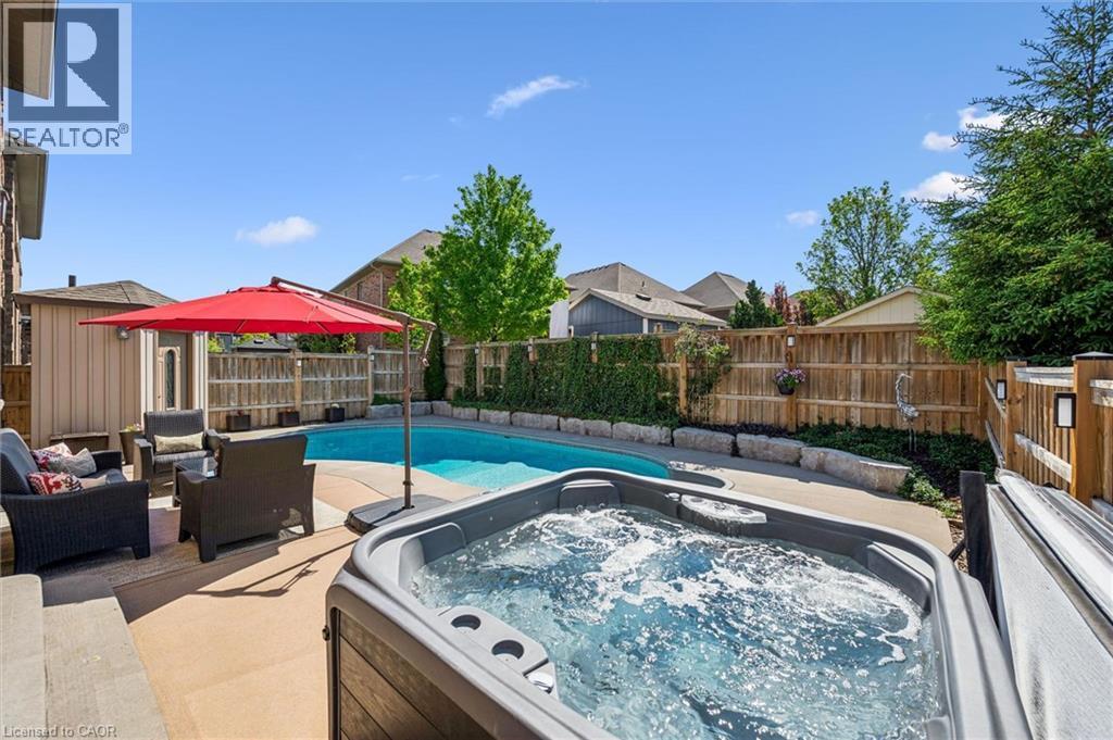 Backyard oasis featuring a sparkling inground pool and a bubbling hot tub. - 828 Copper Ridge Drive, Waterloo, ON - Outdoor With In Ground Pool
