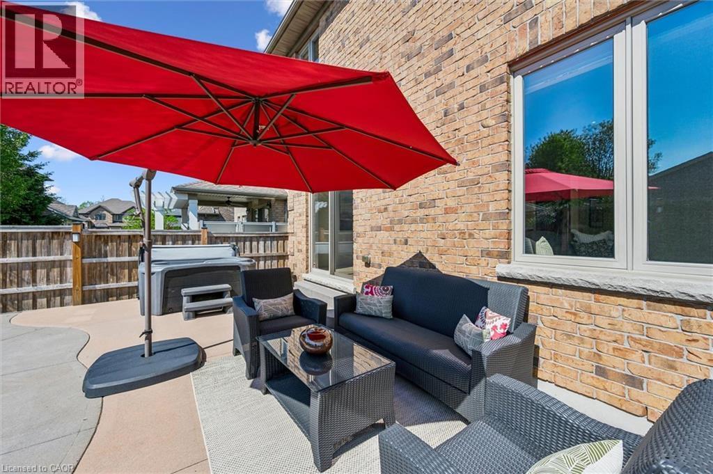 Outdoor patio featuring a hot tub, concrete hardscaping, and a brick exterior facade with a window. - 828 Copper Ridge Drive, Waterloo, ON - Outdoor With Deck Patio Veranda With Exterior