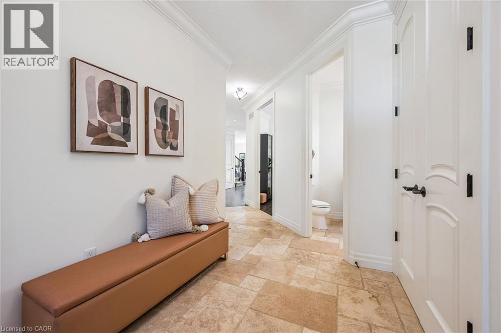 Hallway featuring natural stone tile flooring, white crown molding, and white paneled doors with dark hardware. - 828 Copper Ridge Drive, Waterloo, ON - Indoor Photo Showing Other Room