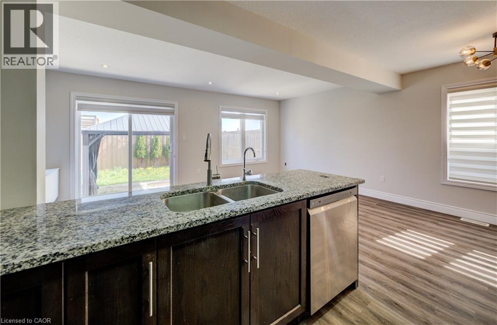 Kitchen island featuring a dual stainless steel sink, a stainless steel dishwasher, and a speckled countertop - 80 Miranda Path, Elmira, ON - Indoor Photo Showing Kitchen With Double Sink