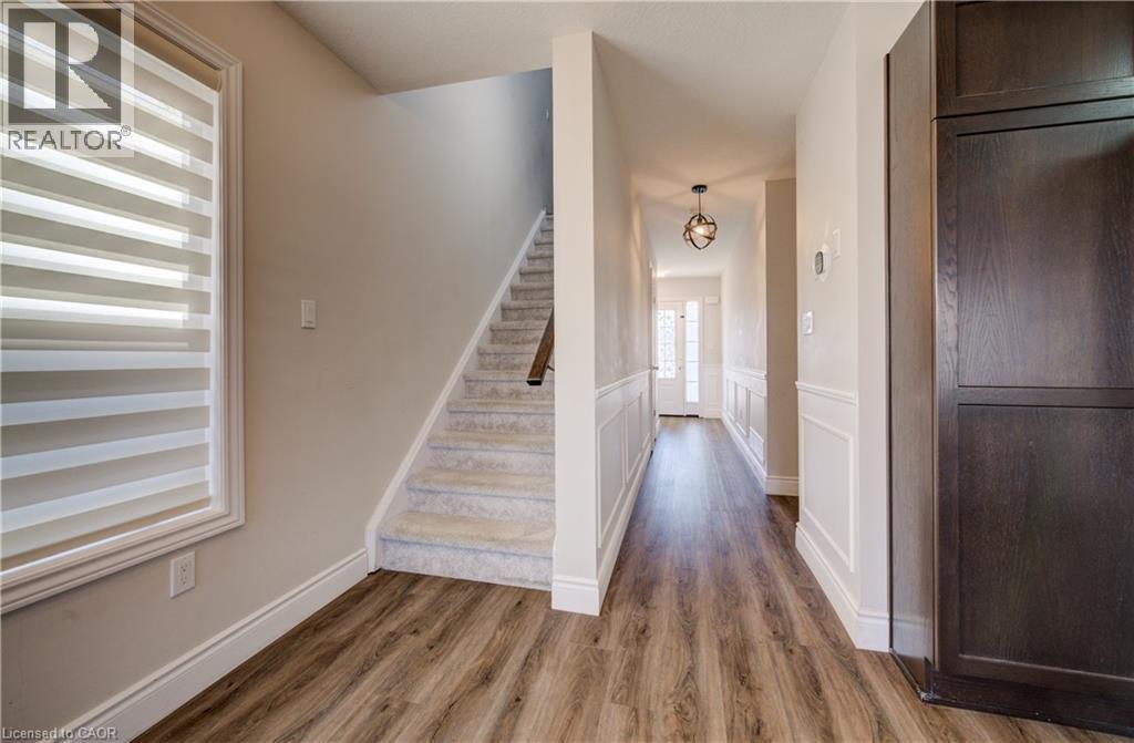 Foyer featuring wood-finish flooring, wainscoting, a carpeted staircase, and a contemporary ceiling light fixture - 80 Miranda Path, Elmira, ON - Indoor Photo Showing Other Room