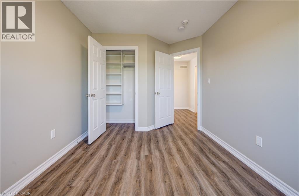 Interior room featuring wood-finish flooring, light-toned wall paint, white baseboards, and a built-in closet with shelving - 80 Miranda Path, Elmira, ON - Indoor Photo Showing Other Room