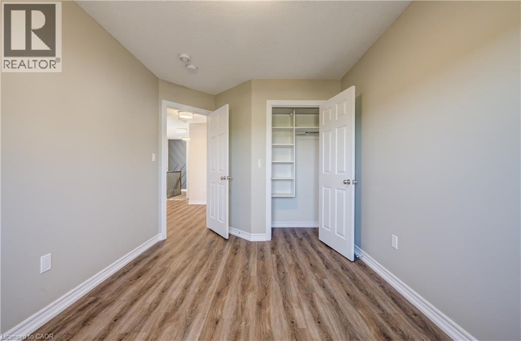 Interior room featuring wood-finish flooring, light neutral wall paint, and white baseboards - 80 Miranda Path, Elmira, ON - Indoor Photo Showing Other Room