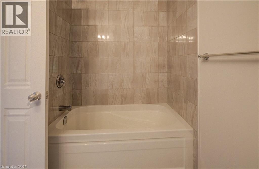 White bathtub with chrome fixtures and light-toned, vertically oriented wall tiling - 80 Miranda Path, Elmira, ON - Indoor Photo Showing Bathroom