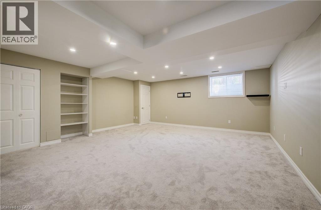 Spacious room featuring light gray carpeting, recessed ceiling lighting, a built-in shelving unit, and a window with blinds - 80 Miranda Path, Elmira, ON - Indoor Photo Showing Basement