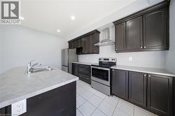 Contemporary kitchen featuring dark wood cabinetry, light countertops, stainless steel appliances, a center island with sink, and tile flooring - 