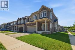 Stately residence featuring a covered front porch, a two-car garage, and a combination of stone and stucco exterior finishes - 