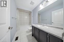 Bathroom featuring a white subway-tiled tub and shower combination, a dark vanity with a light-toned countertop, and a large wall-mounted mirror - 