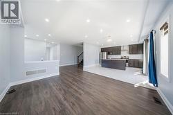 Open-concept living area featuring wood-finish flooring, recessed lighting, and a kitchen with dark cabinetry and stainless steel appliances - 