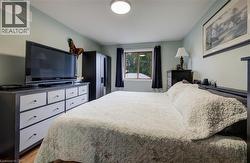 Hardwood-style flooring, light-toned walls, and a window with dark drapery - 