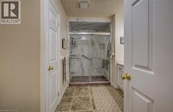 Tiled flooring, walk-in shower with glass enclosure, integrated shelving, and support bars, vanity with countertop - 