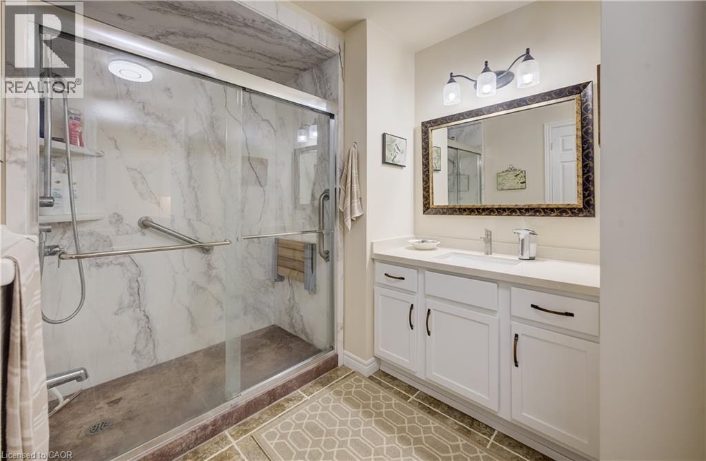 Glass-enclosed shower with a marble-effect surround and grab bars - 16 Steed Court, Brantford, ON