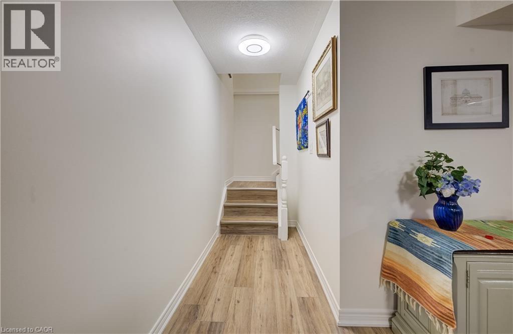 Wood-finish flooring throughout, white painted walls, and a modern flush-mount ceiling light fixture - 16 Steed Court, Brantford, ON