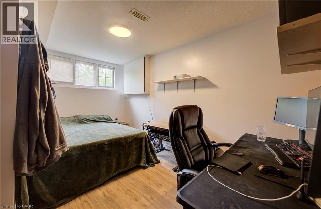 Light-toned wall paint, wood-finish flooring, two rectangular windows, and a ceiling-mounted light fixture - 16 Steed Court, Brantford, ON
