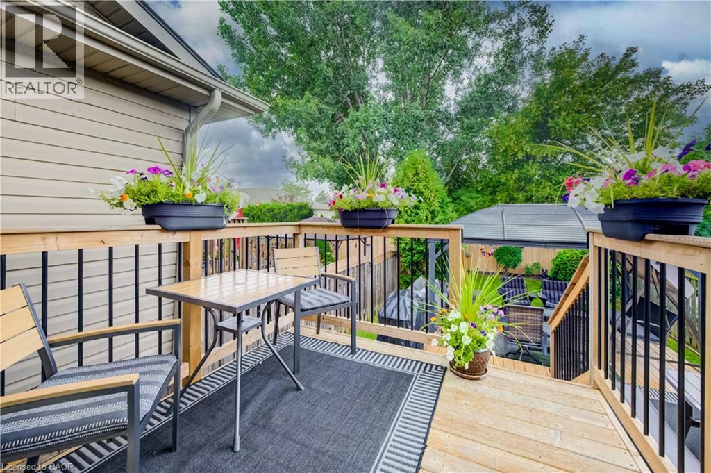 Expansive wood deck with black metal balusters, integrated wood railing, and a large gazebo - 16 Steed Court, Brantford, ON