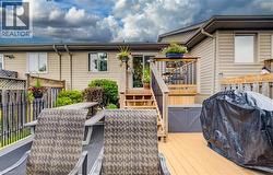 Multi-level wood-finish deck with black metal railings, leading to an upper landing with sliding glass door access - 