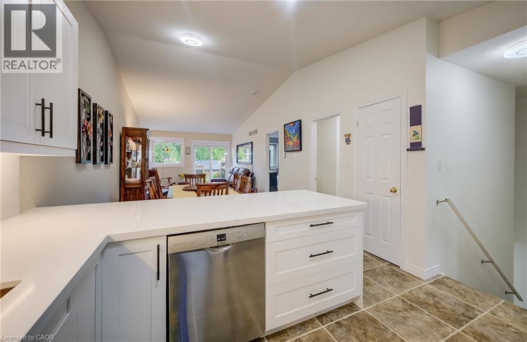 Kitchen island with white cabinetry, stainless steel dishwasher, and white countertops - 16 Steed Court, Brantford, ON