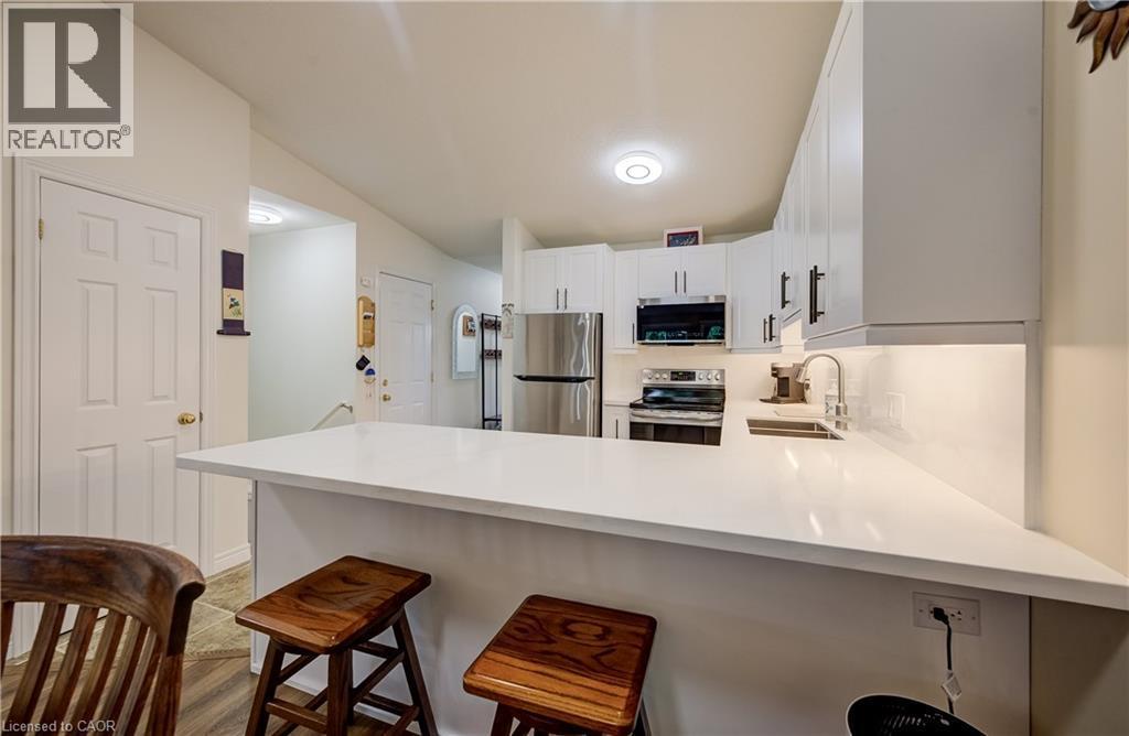 Kitchen featuring white cabinetry, stainless steel appliances, a white countertop peninsula, and an undermount sink - 16 Steed Court, Brantford, ON