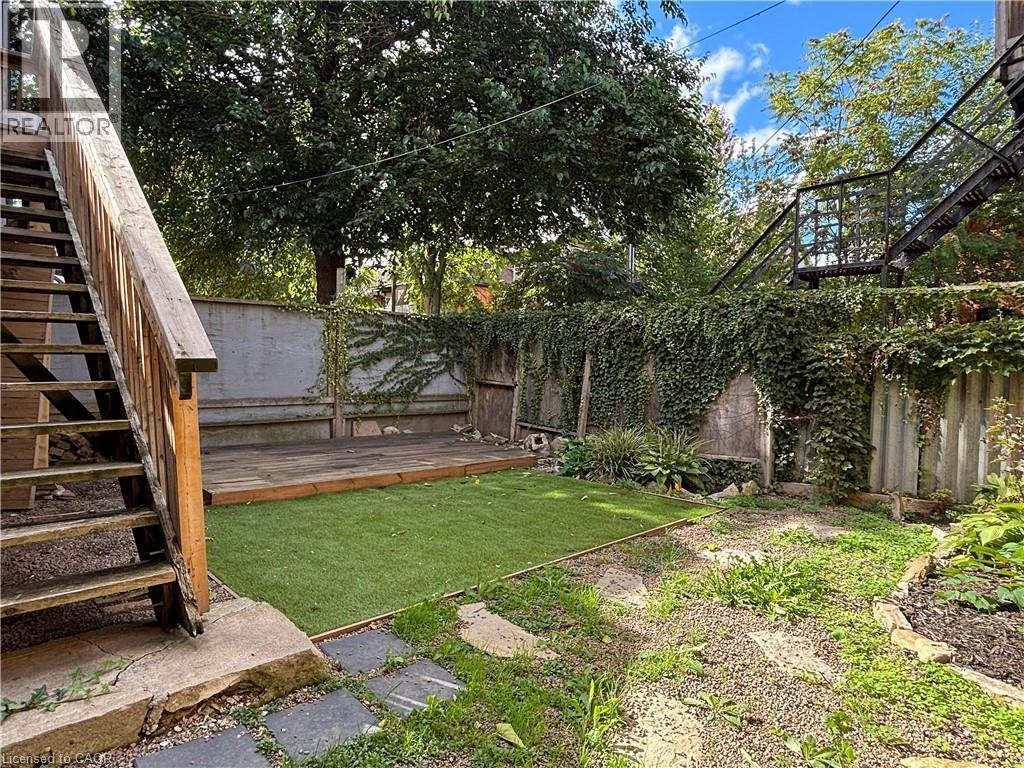 Outdoor shared space featuring a wood deck, artificial turf, and stepping stones - 76 Wentworth Street S, Hamilton, ON