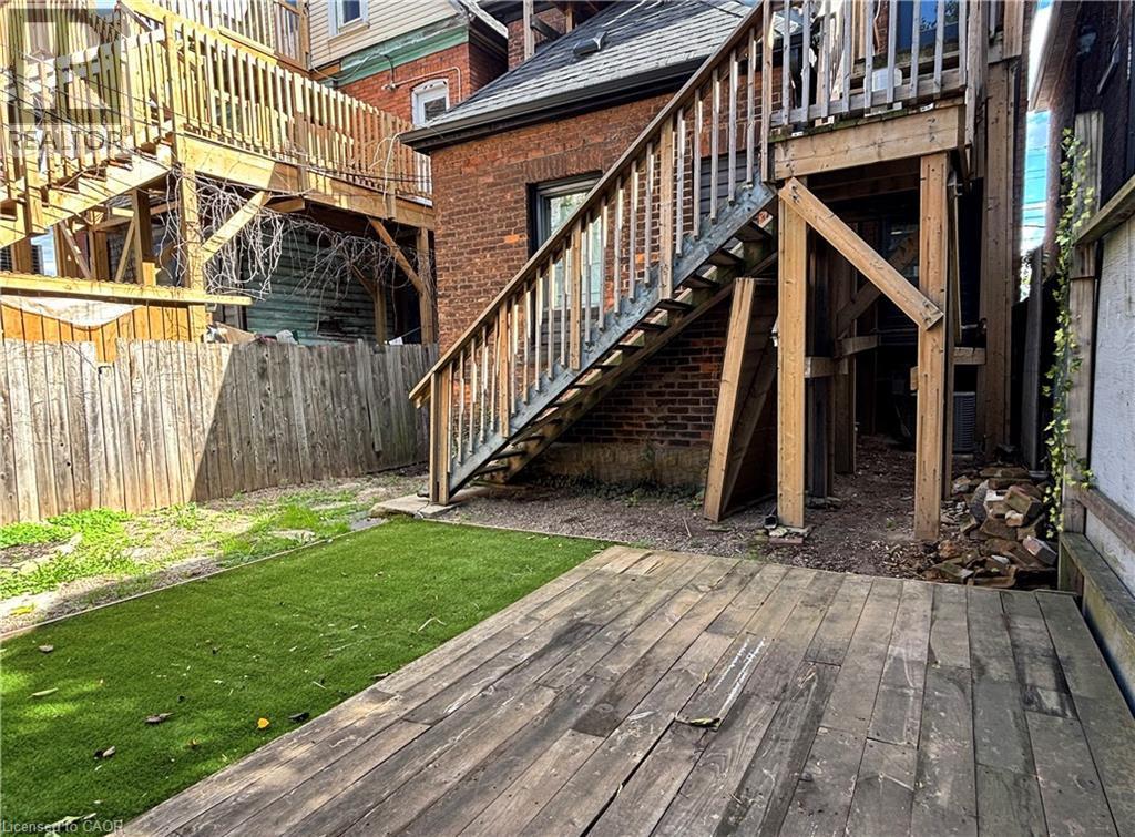 Exterior featuring a wooden deck, a section of artificial turf, and a wooden privacy fence - 76 Wentworth Street S, Hamilton, ON