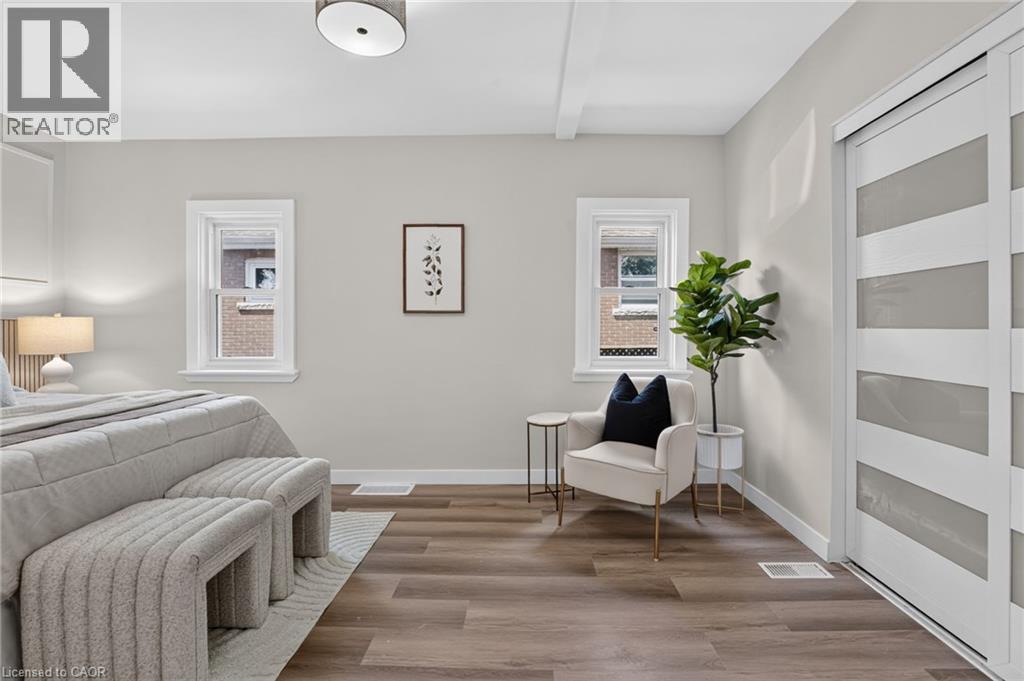 Wood-finish flooring with white trim, two windows, and a ceiling-mounted light fixture - 43 E Brucedale Avenue E, Hamilton, ON
