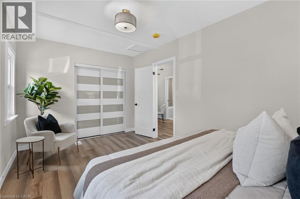 Wood-finish flooring, white trim, sliding closet doors with frosted panels, and a drum pendant light fixture - 43 E Brucedale Avenue E, Hamilton, ON