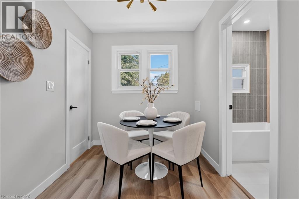 Wood-finish flooring, white interior doors with black hardware, double casement windows, and a bathroom featuring vertical subway tile - 43 E Brucedale Avenue E, Hamilton, ON