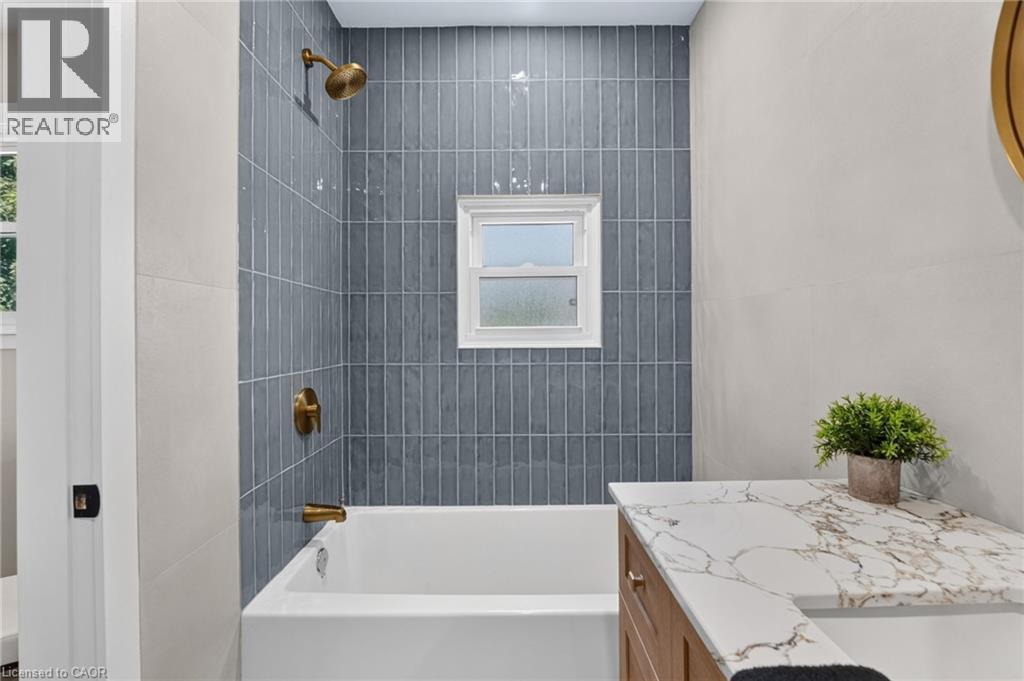Tub and shower combination with vertical tile surround and brass fixtures - 43 E Brucedale Avenue E, Hamilton, ON
