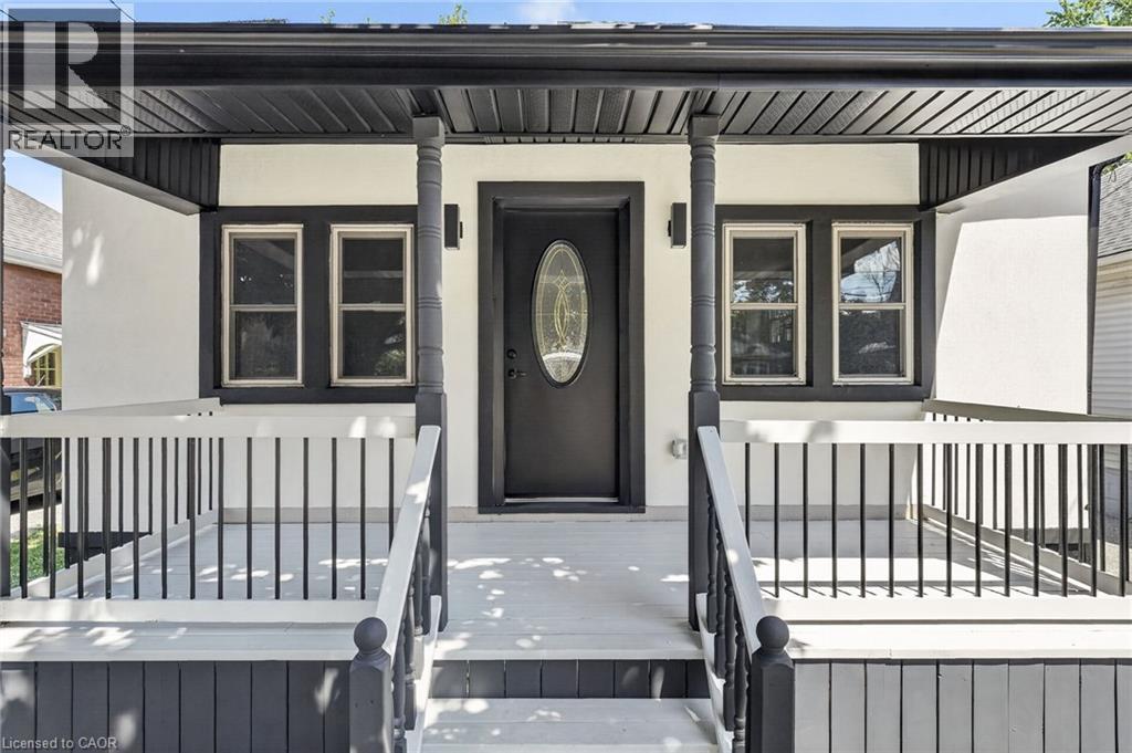 Covered front porch with black railings, decorative porch columns, and a black front door with oval-shaped glass insert - 43 E Brucedale Avenue E, Hamilton, ON