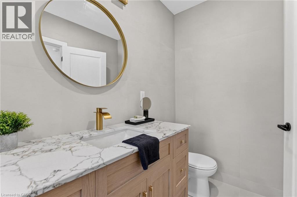Wood-finish vanity with gold-tone hardware, integrated sink, and stone-finish countertop - 43 E Brucedale Avenue E, Hamilton, ON