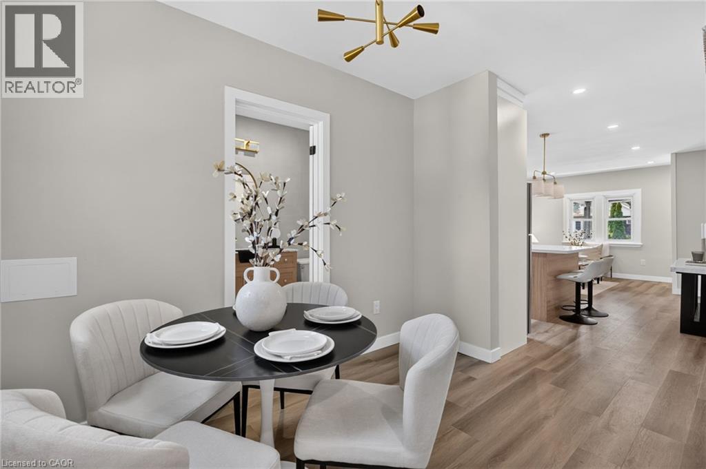 Wood-finish flooring, recessed lighting, contemporary ceiling light fixture, doorway with white trim, and a built-in kitchen island with a light-toned countertop - 43 E Brucedale Avenue E, Hamilton, ON