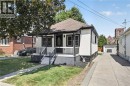 Front porch with dark railing, white exterior, and a detached garage with a long driveway - 43 Brucedale Avenue E, Hamilton, ON 