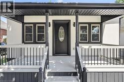 Covered front porch with black railings, decorative porch columns, and a black front door with oval-shaped glass insert -