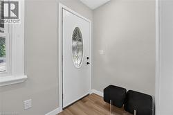 Entryway featuring a white door with decorative glass, wood-finish flooring, and light-toned walls -