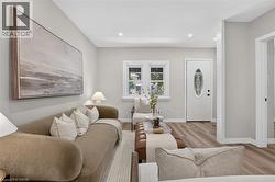 Recessed lighting, wood-finish flooring, white trim, and a white entry door with an oval glass insert -