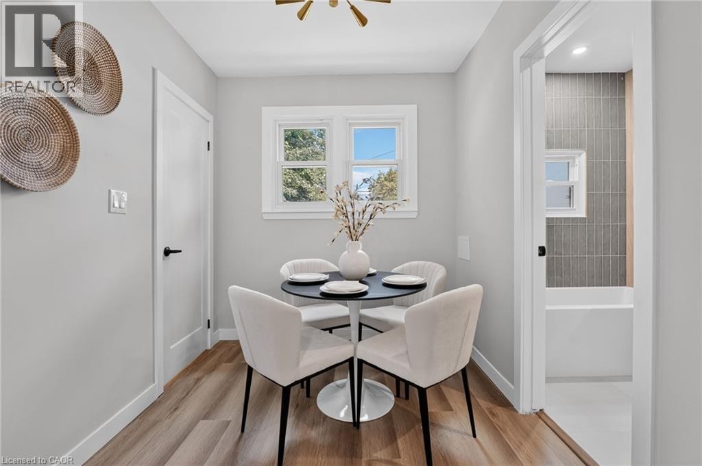 Wood-finish flooring, white interior doors with black hardware, double casement windows, and a bathroom featuring vertical subway tile - 43 Brucedale Avenue E, Hamilton, ON